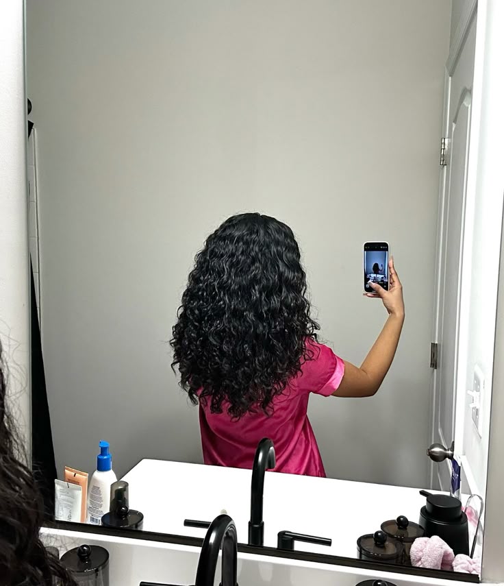 a girl checking her hair curl pattern with mirror selfie