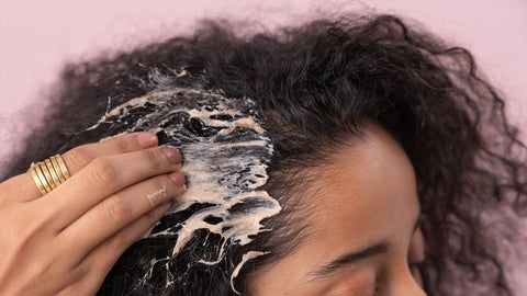someone applying hair cream to her hair