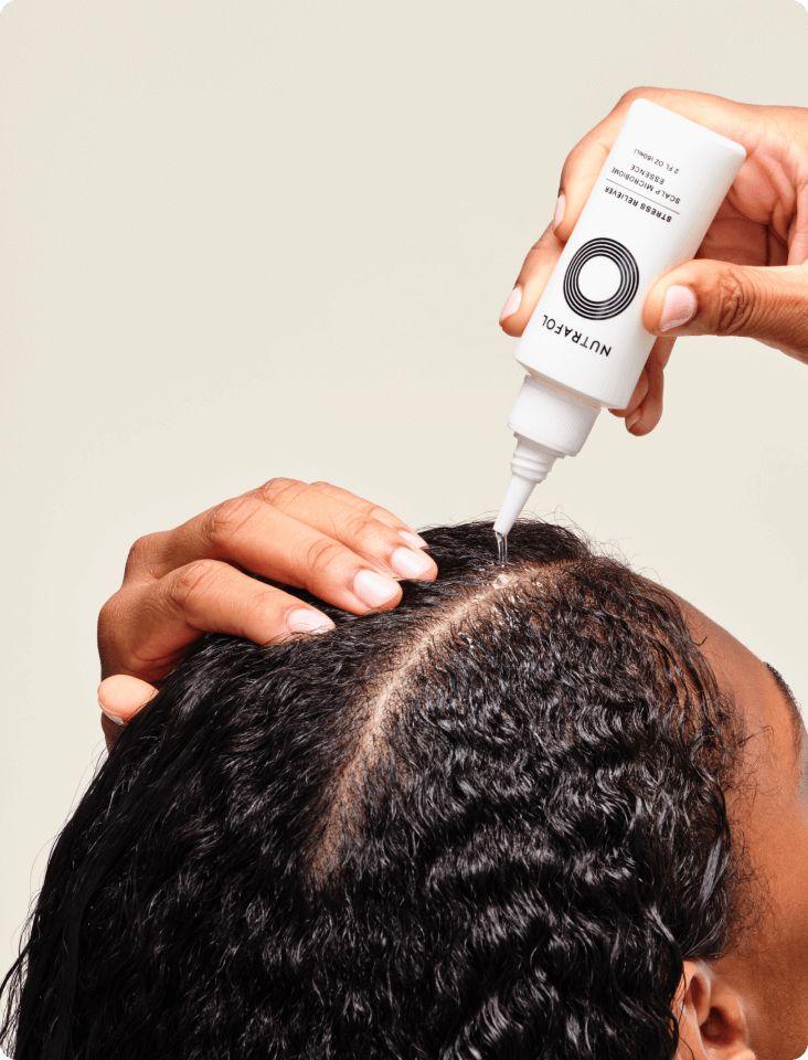 someone applying hair growth oil to her damp hair