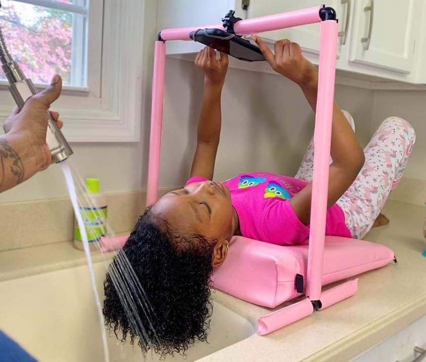 a childing washing her hair while pressing her phone