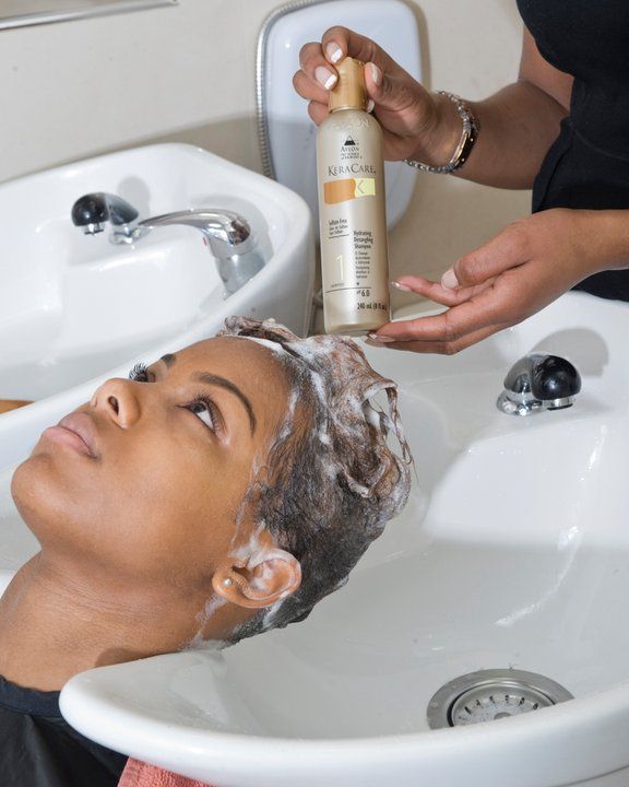 a lady applying deep conditioner to   her client's hair