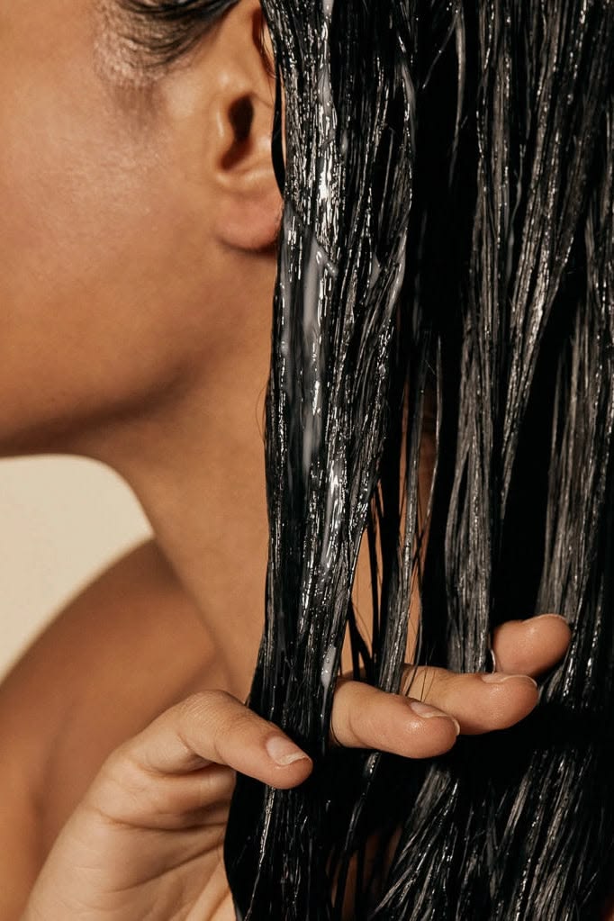 someone detangling her hair with cream
