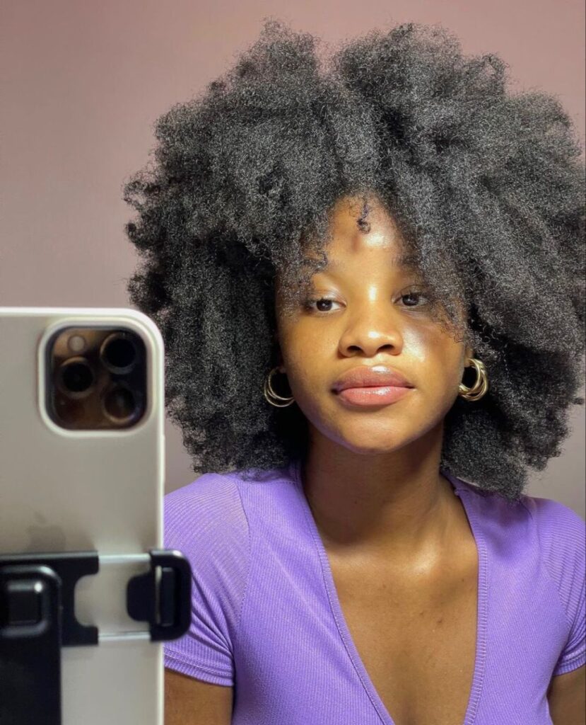 a lady with full afro hair with her phone camera set
