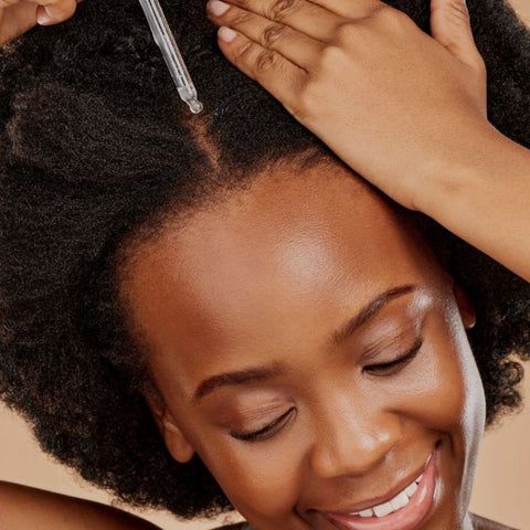 someone feeding her scalp with oil to build healthy afro hair