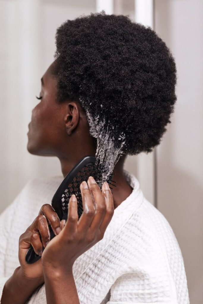 someone moisturizing her hair as part of hair growth routine for afro hair