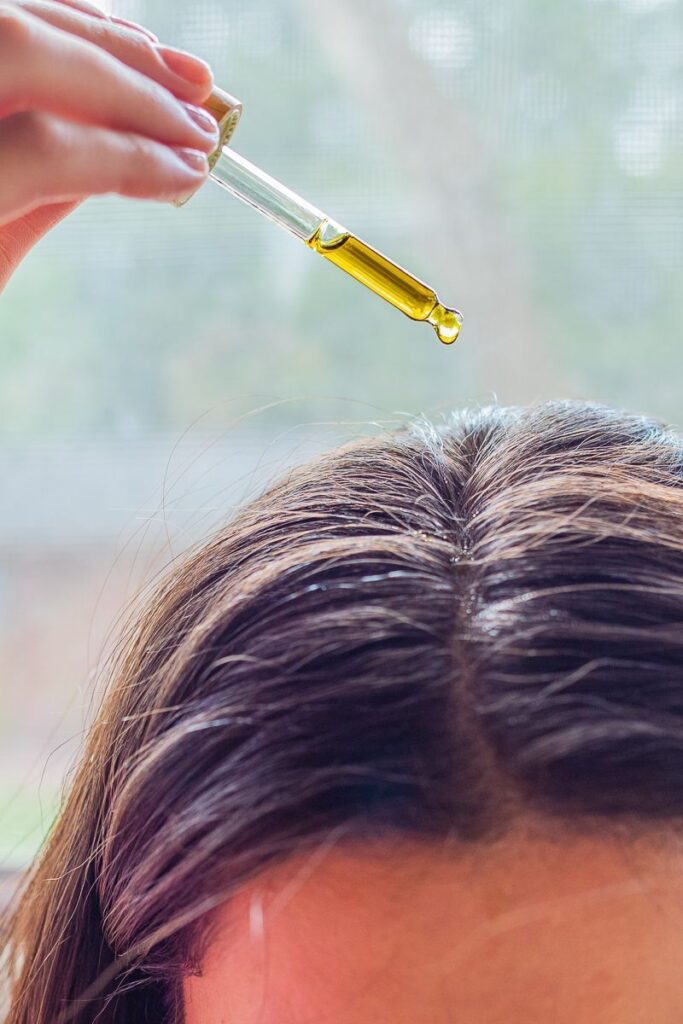 someone dropping oil on her hair