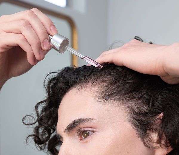 someone applying hair growth oil to the hair
