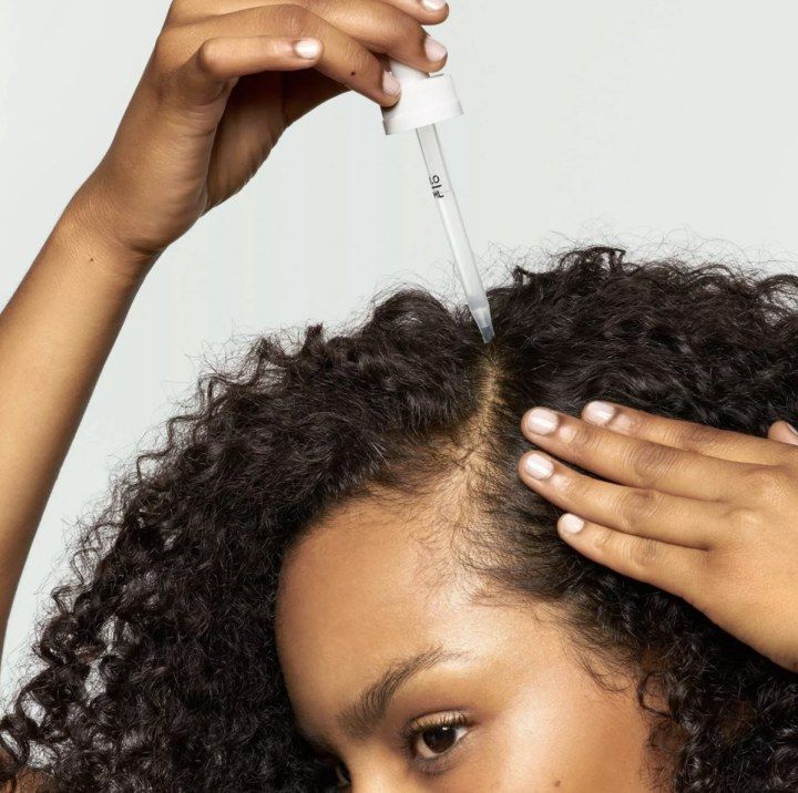 someone applying oil to her curly hair