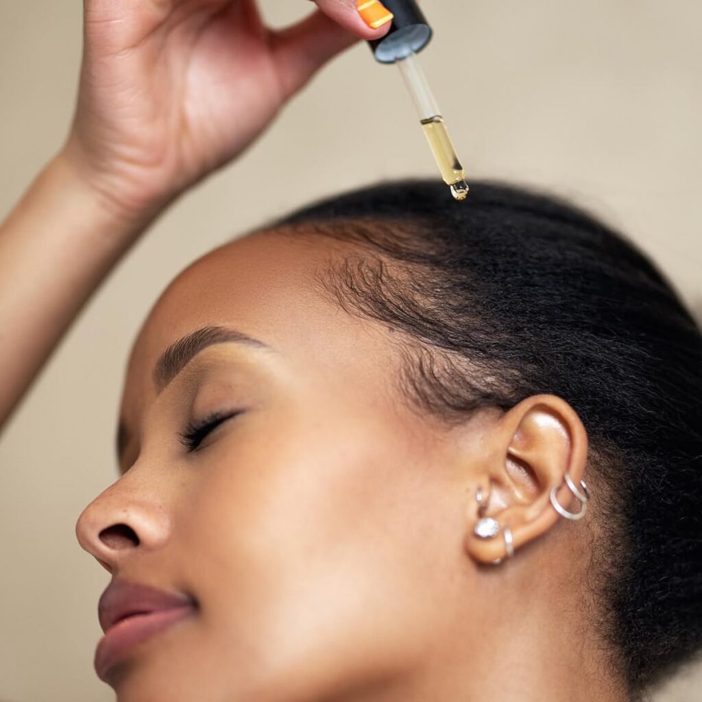 someone applying oil to her hair as part of hair growth routine for afro hair