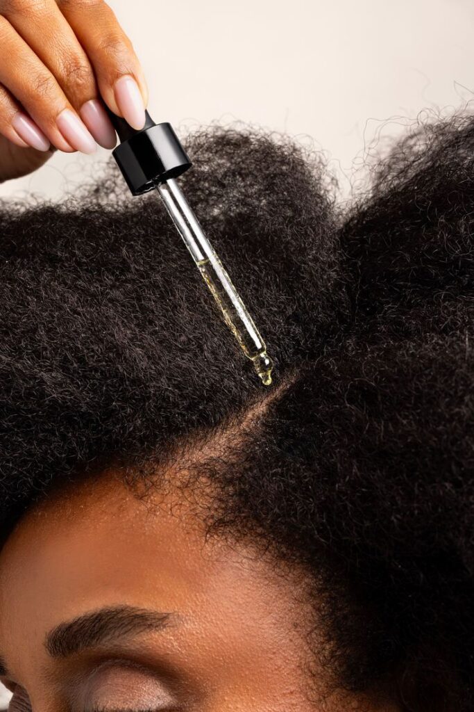 someone applying oil to her scalp as pert of her healthy scalp habit