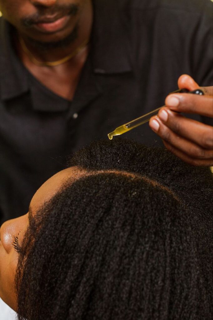 someone applying oil to the scalp as part of length retention tips