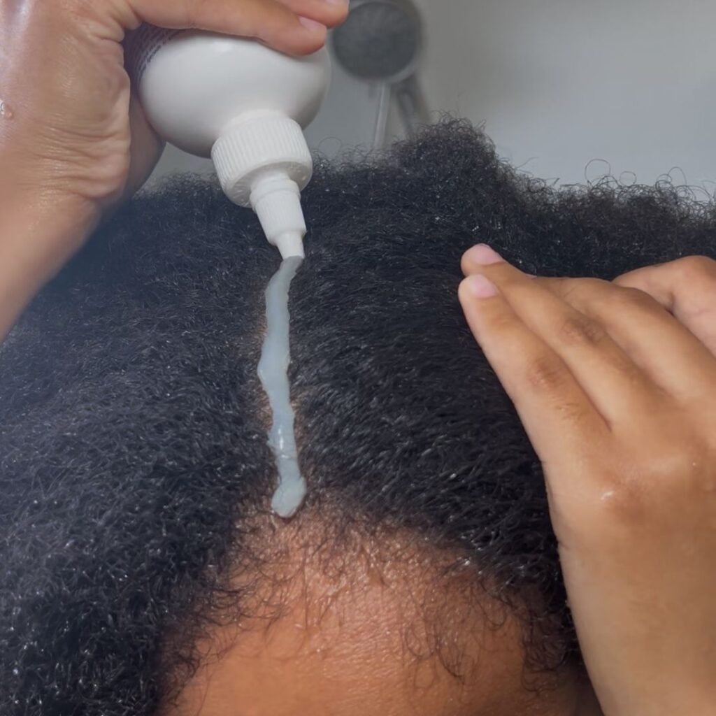 someone applying a cleaning scalp product as part of her healthy scalp habit