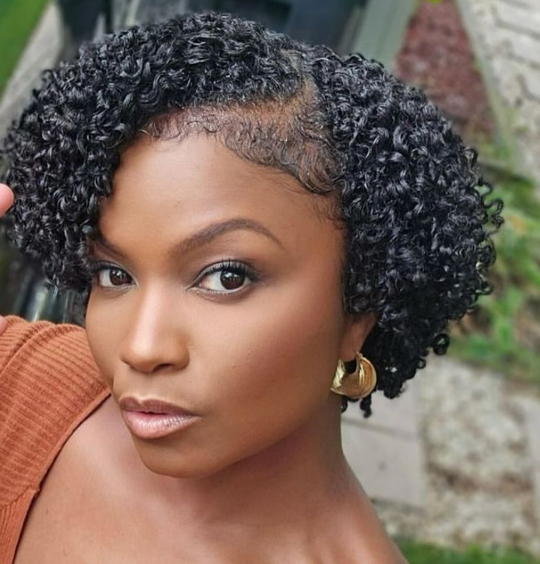 Girl styling her natural hair in neat, sectioned curls.