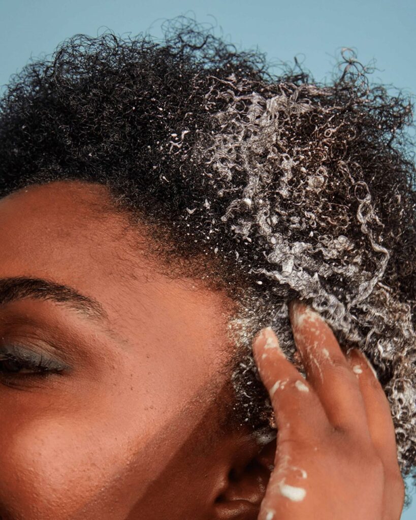 someone applying shampoo to her hair