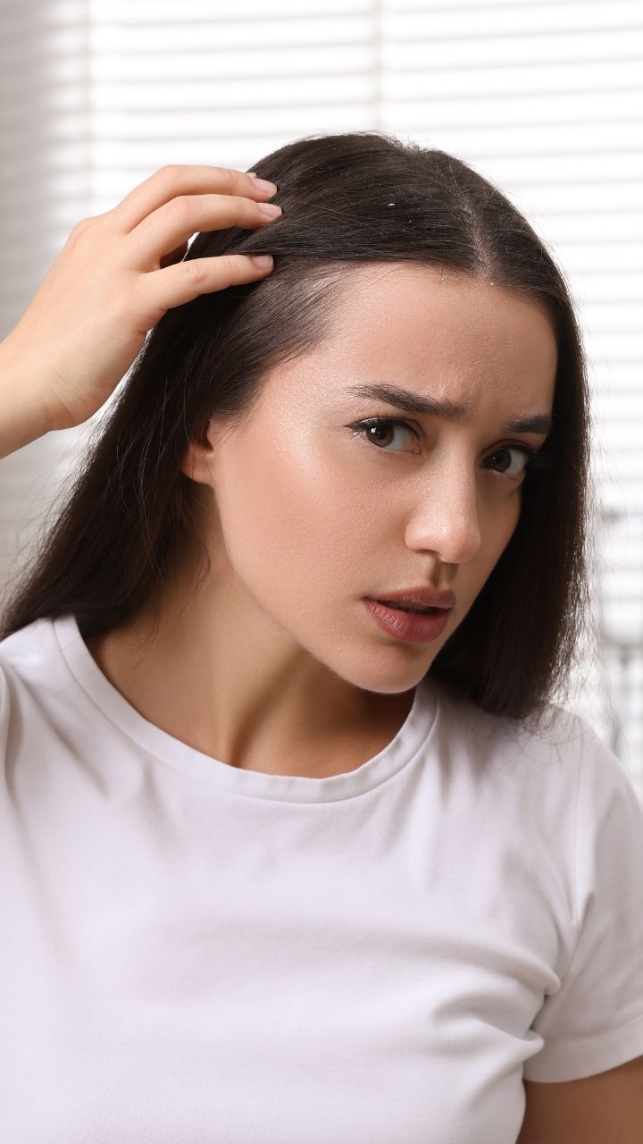 a lady looking at her scalp in a mirror