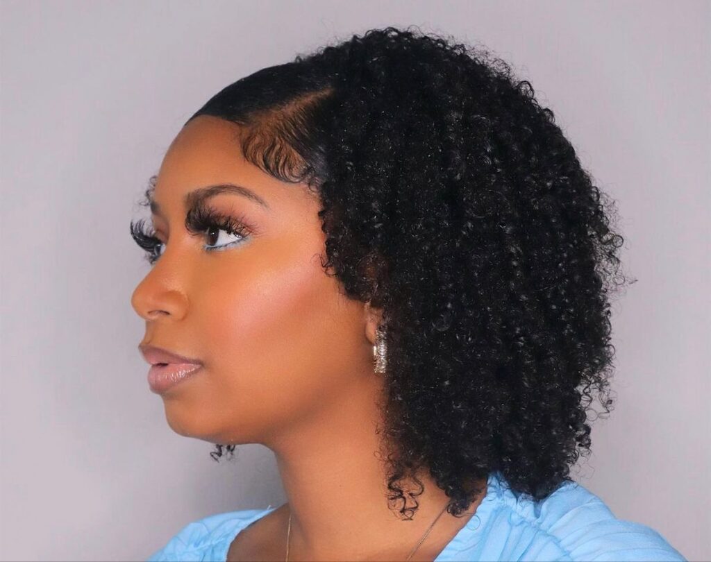 Deep side-part natural hairstyle with defined curls.