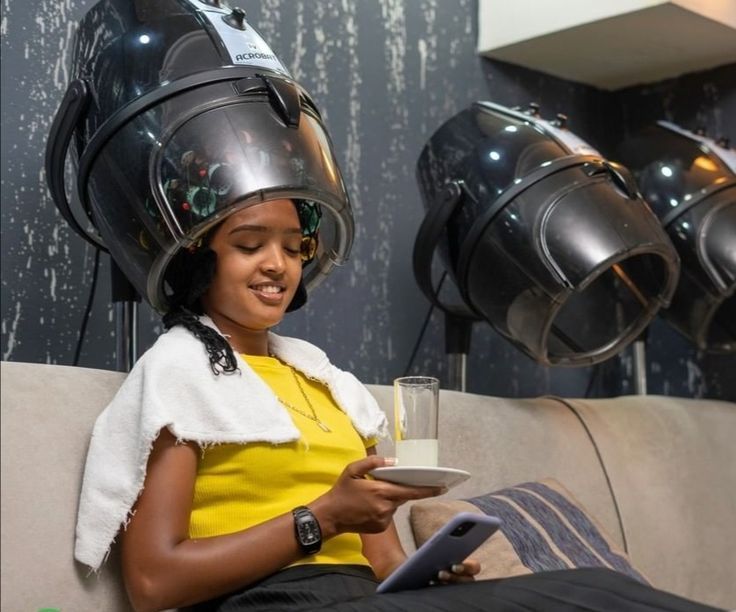 someone drying her hair with standing dryer on her wash day