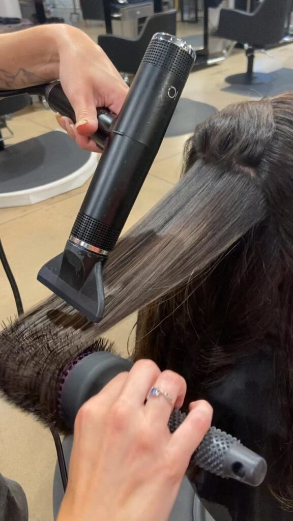 someone using comb attachment while blow drying afro hair without damage