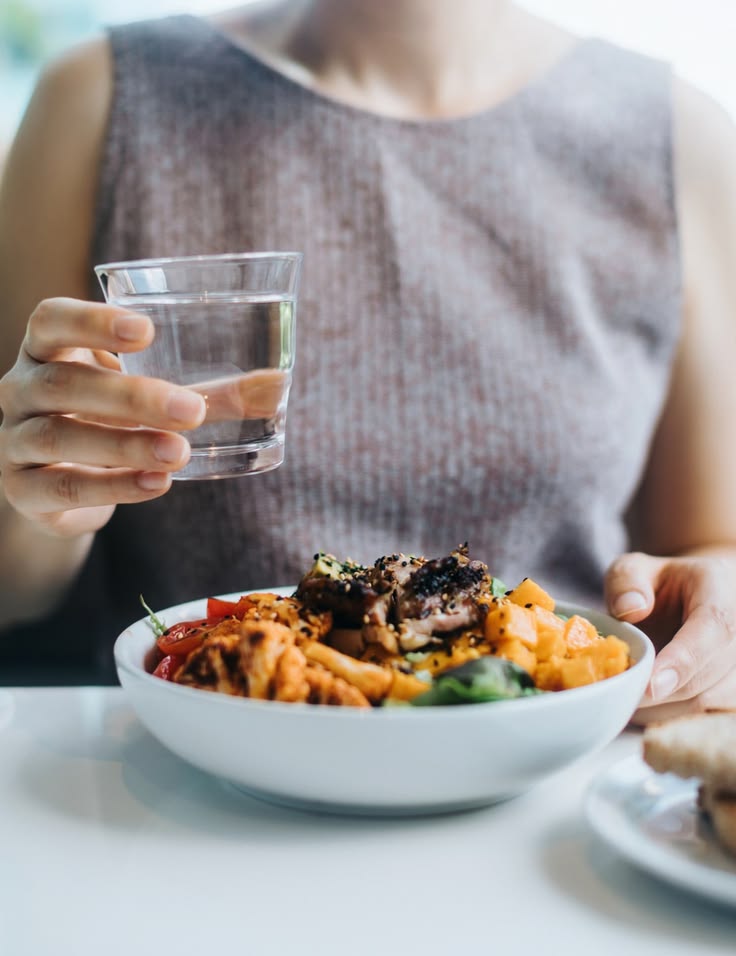 someone drinking water as she have her healthy meal