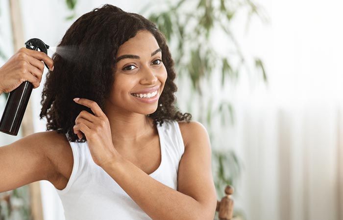 someone using heat protectant on her hair