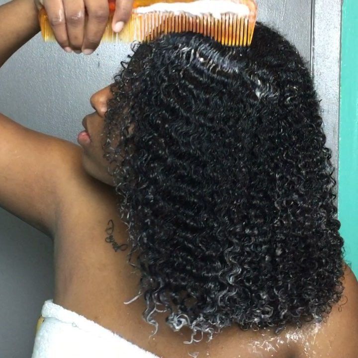 someone moisturizing her afro hair under wig