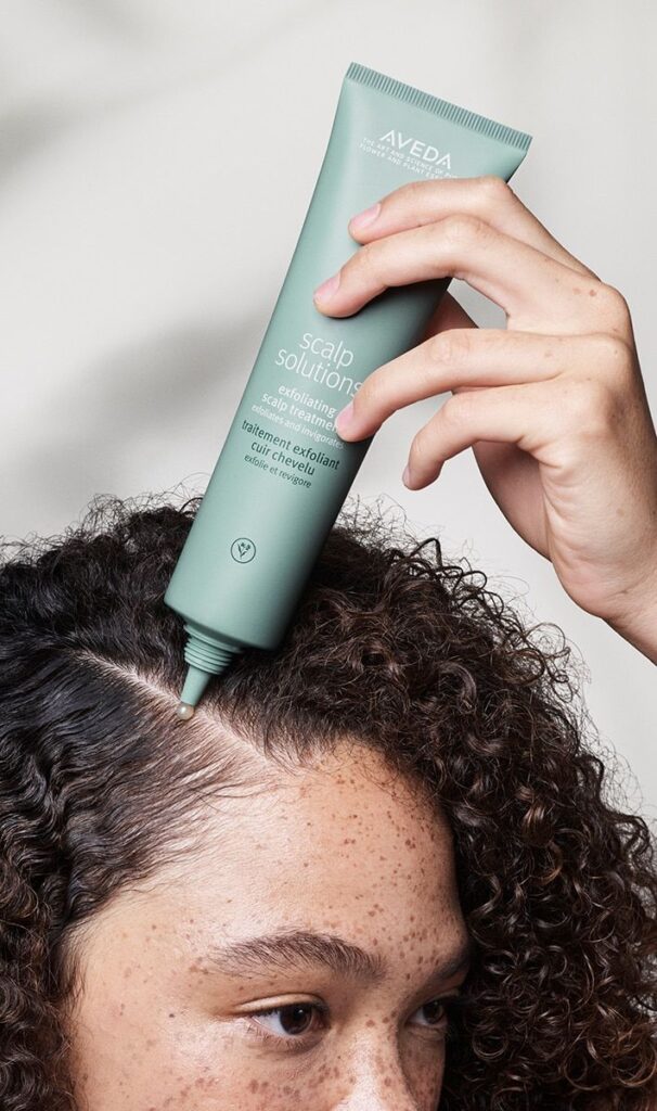 someone applying scalp treatment to her curly hair