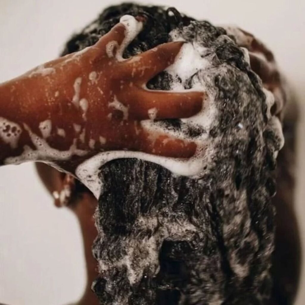 someone washing her scalp as one of the healthy scalp habits