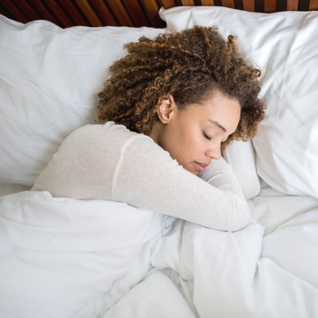 someone sleeping on a cotton pillow without hair cover as one of the hidden mistakes that's breaking your hair every week
