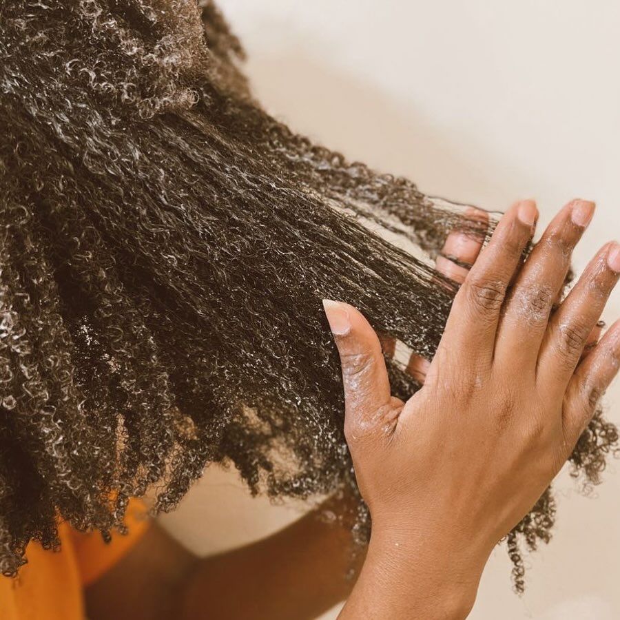 someone applying conditioner to her hair on her 4A hair wash day