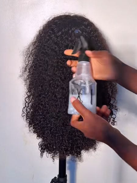 someone applying wig spray on her wig