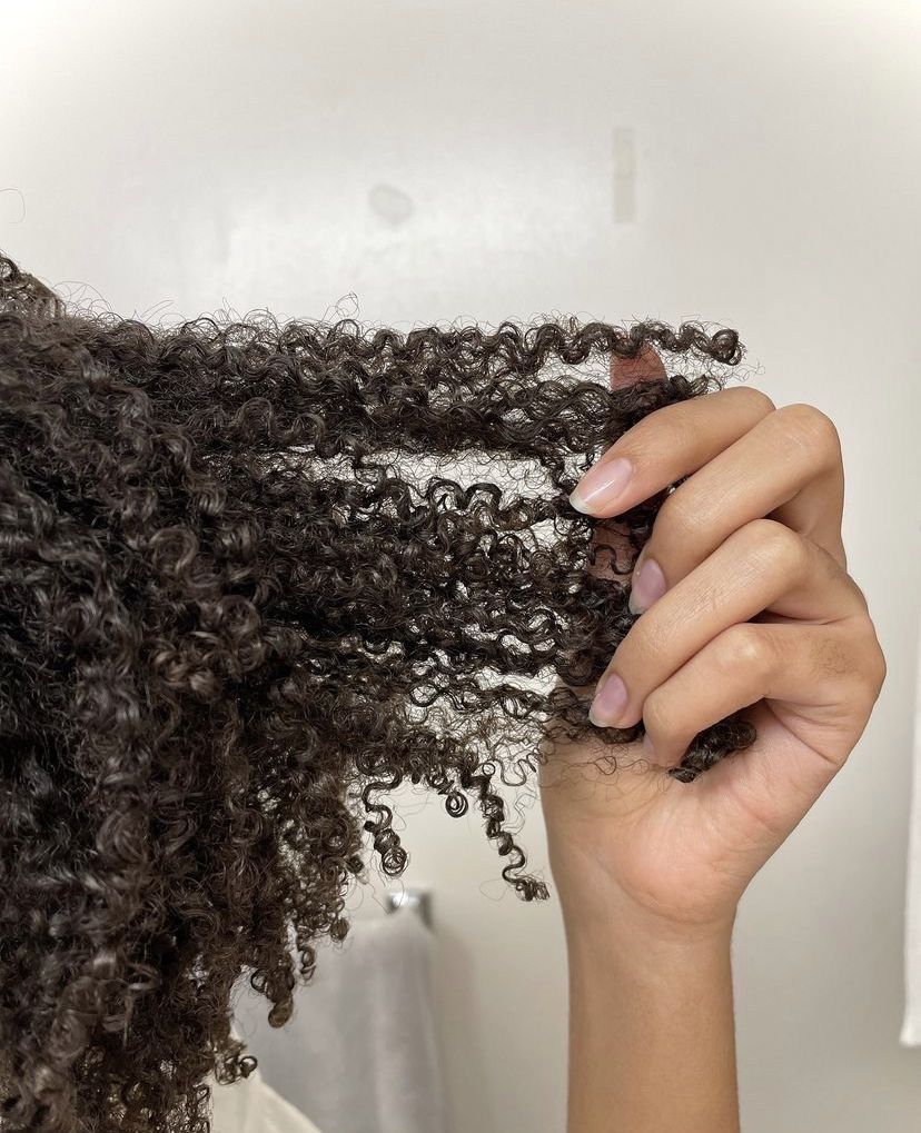 someone checking out her hair curl pattern while getting ready for her 4A hair wash day routine