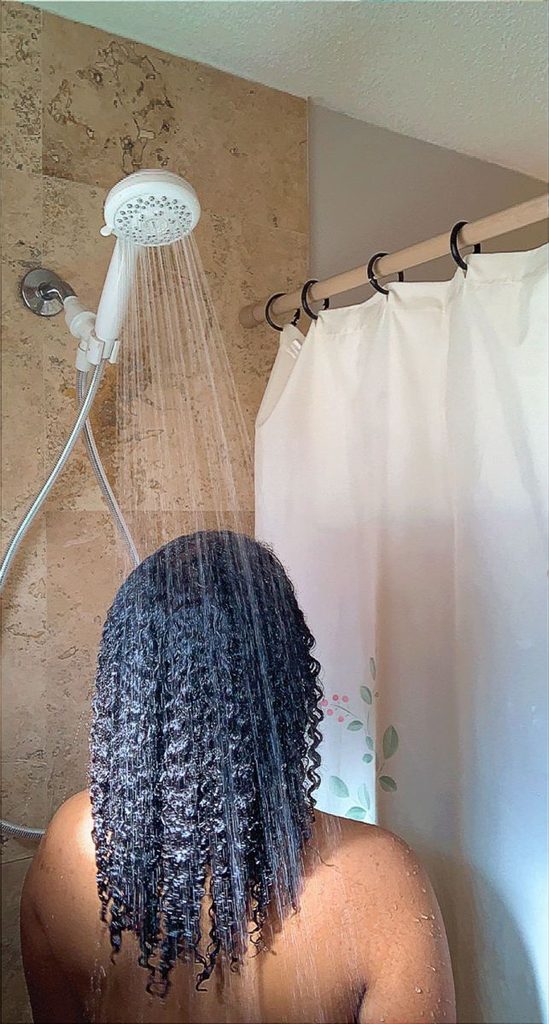 someone rinsing her hair in the shower as part of healthy hair routine ideas