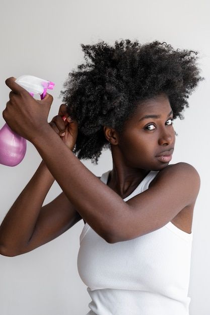 someone applying hair spray to her hair as part of healthy hair routine ideas