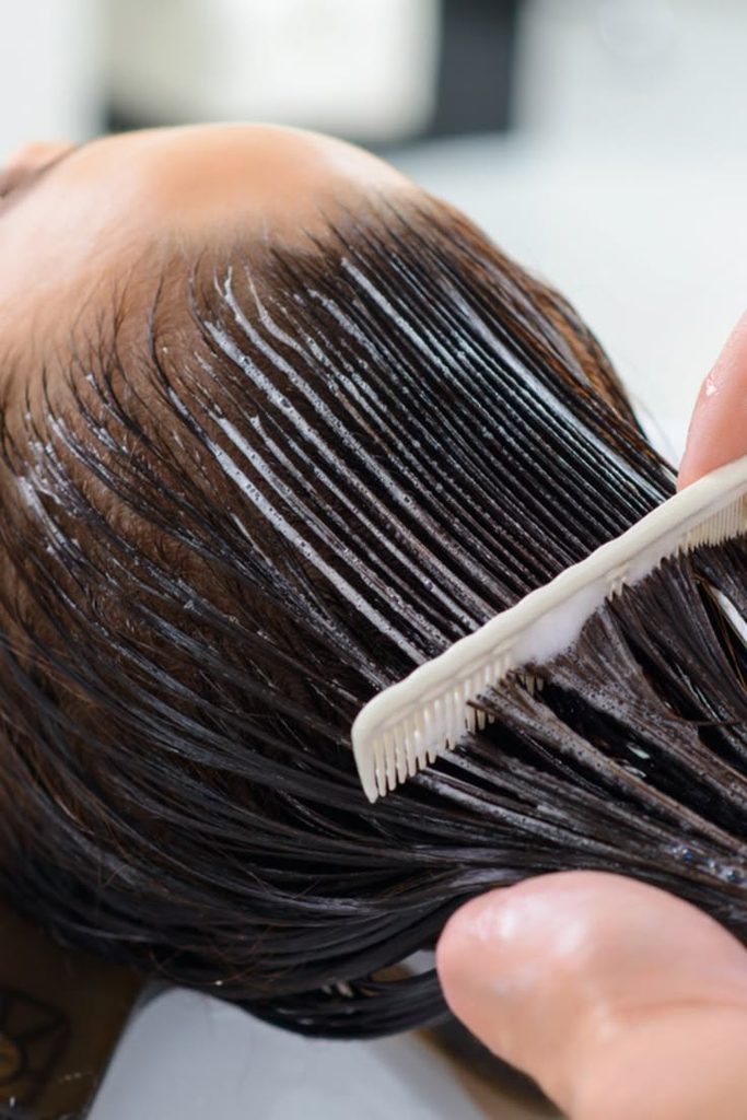 someone giving her hair keratin treatment